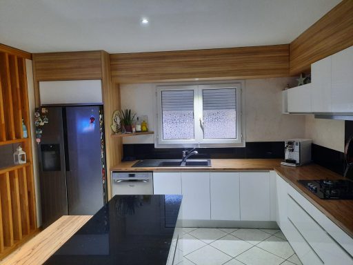 Cuisine moderne avec des meubles en bois clair et un plan de travail noir.