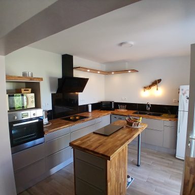 Cuisine moderne avec îlot central, appareils électroménagers en acier inoxydable et armoires grises.